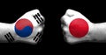 Flags of Japan and South Korea painted on two clenched fists facing each other on black background/.JapanÃ¢â¬âSouth Korea relations